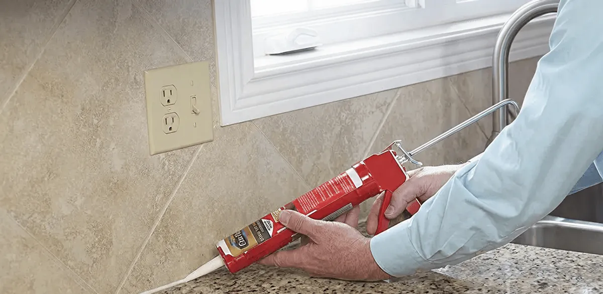 Handyman applying caulk along a kitchen backsplash and countertop seam in Hialeah, FL