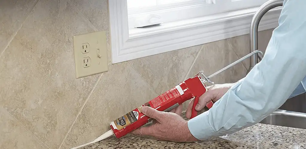 Handyman applying caulk along a kitchen backsplash and countertop seam in Hialeah, FL