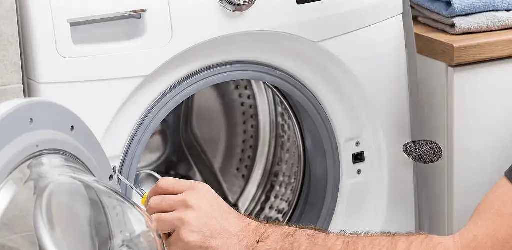Handyman repairing a front-load washing machine and inspecting the drum in Hialeah, FL