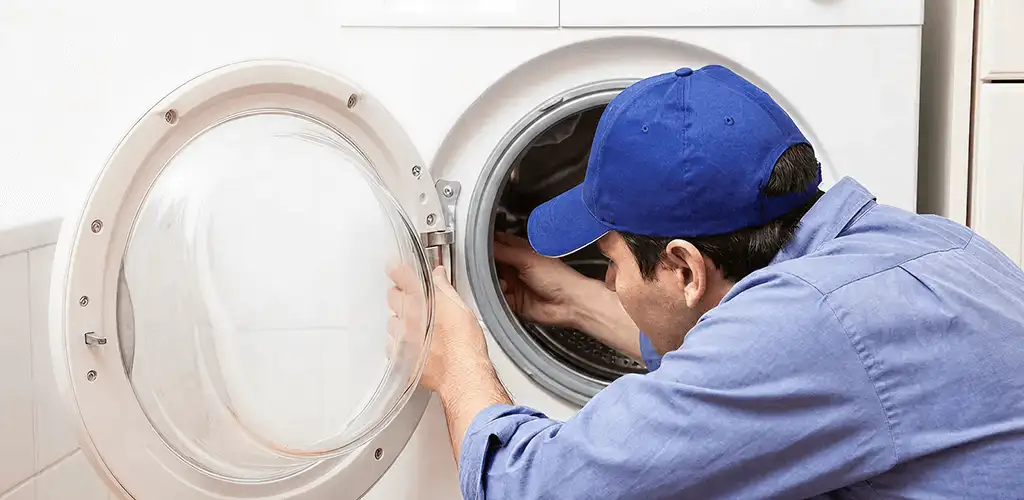 Washing machine repair handyman inspecting a front-load washer drum in Hialeah, FL