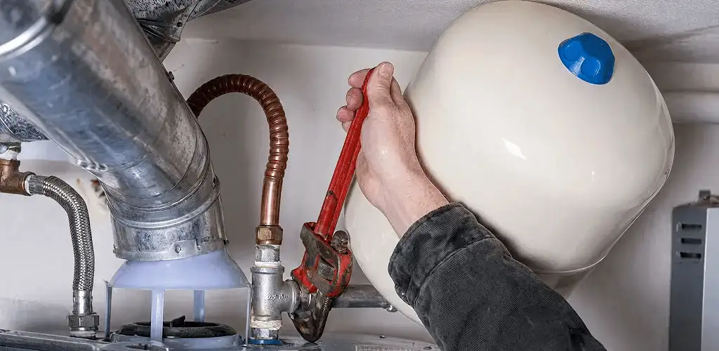 Water heater repair technician tightening plumbing connections near a tank unit in Hialeah, FL