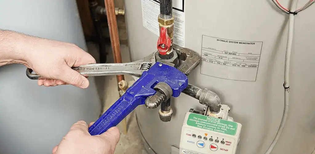 Water heater repair technician tightening the shutoff valve and supply line in Hialeah, FL